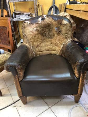 Gros plan sur un fauteuil en cuir déchiré avant restauration par M. Daumas